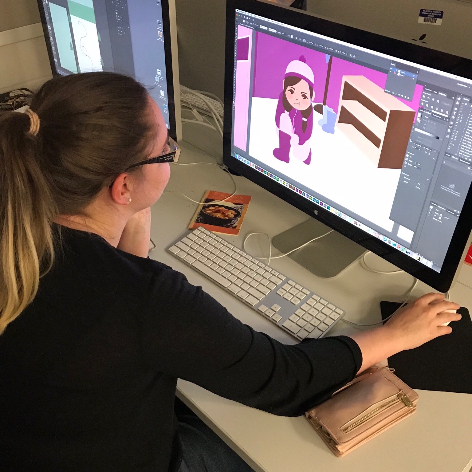 An art + design student works at graphic design on a computer.