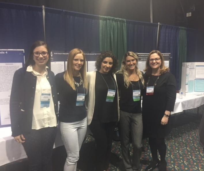 Four graduate students pose with Dr. Dickstein-Fischer in front of their poster presentation at the 2017 MASCA conference