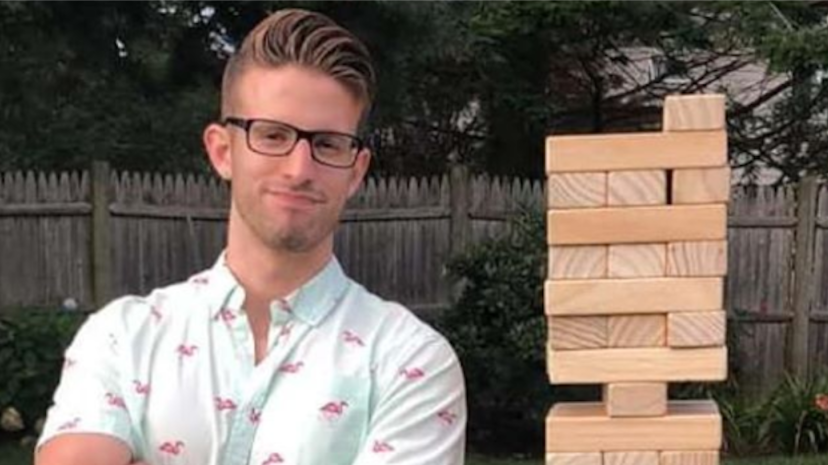 Philosophy alumni Seth Christopher stands next to a Jenga tower in a colorful shirt