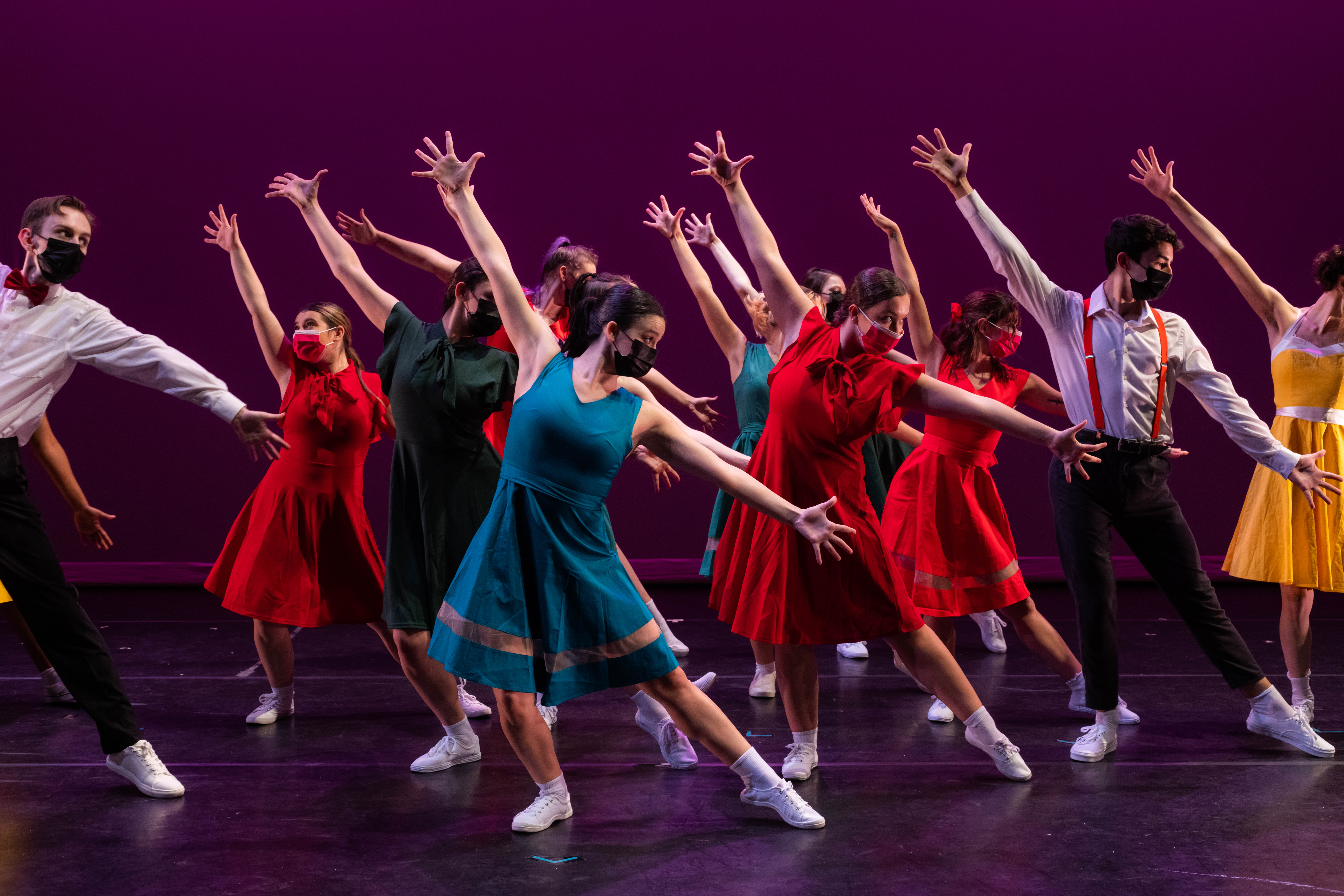 Dancers in colorful close with arms and legs extended