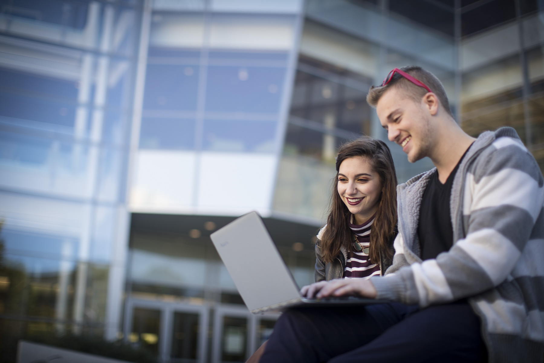 Students study together in front of the library on a sunny day.