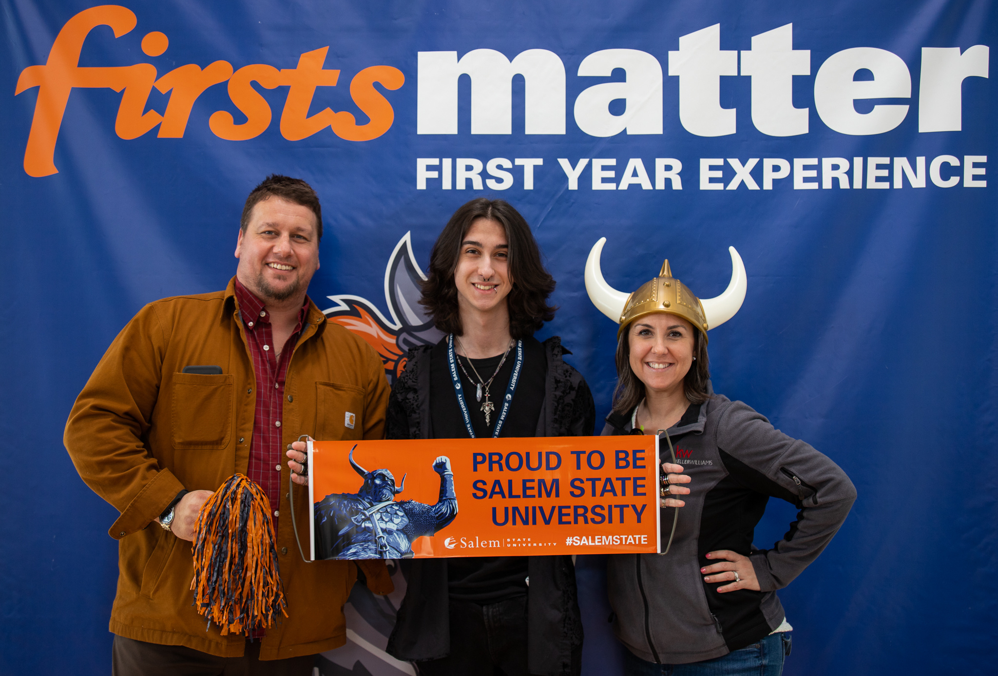 An accepted student and his parents holding a "Proud to be Salem State" banner at Accepted Students Day