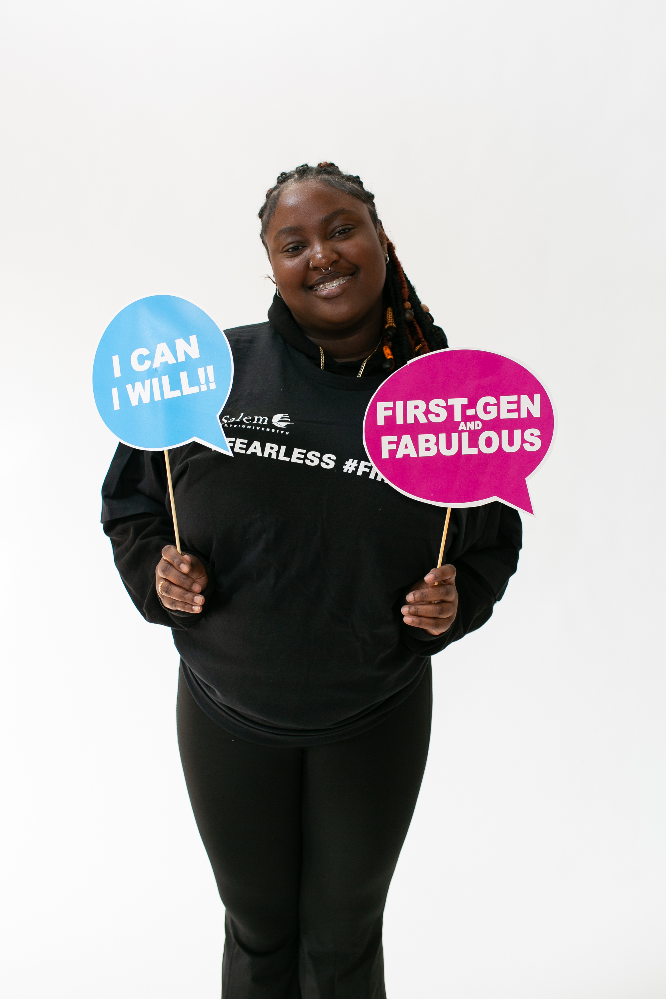Salem State student holds up signs that say "I Can, I will" and "First-gen and fabulous"