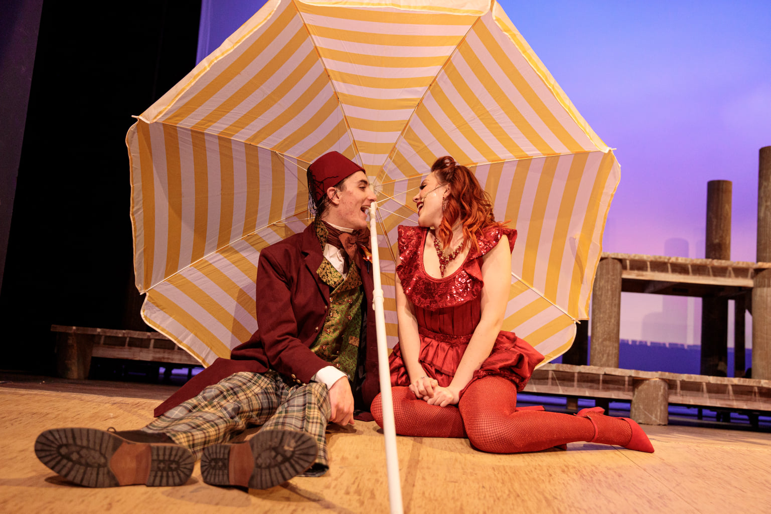 Skin of Our Teeth acting photo with a big yellow-and-white-striped umbrella.