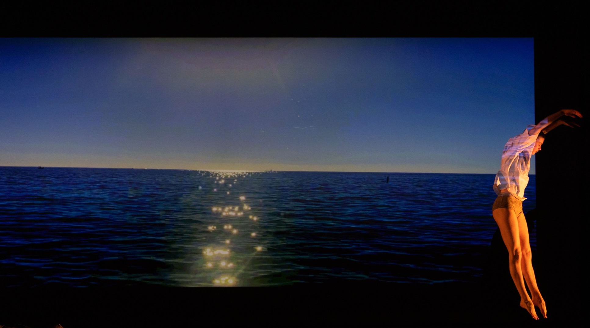 Person jumping in the air in front of an image of the ocean