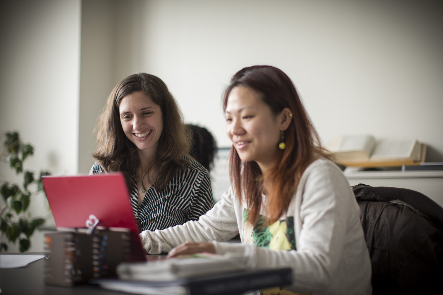 Two women looking at a red laptop.