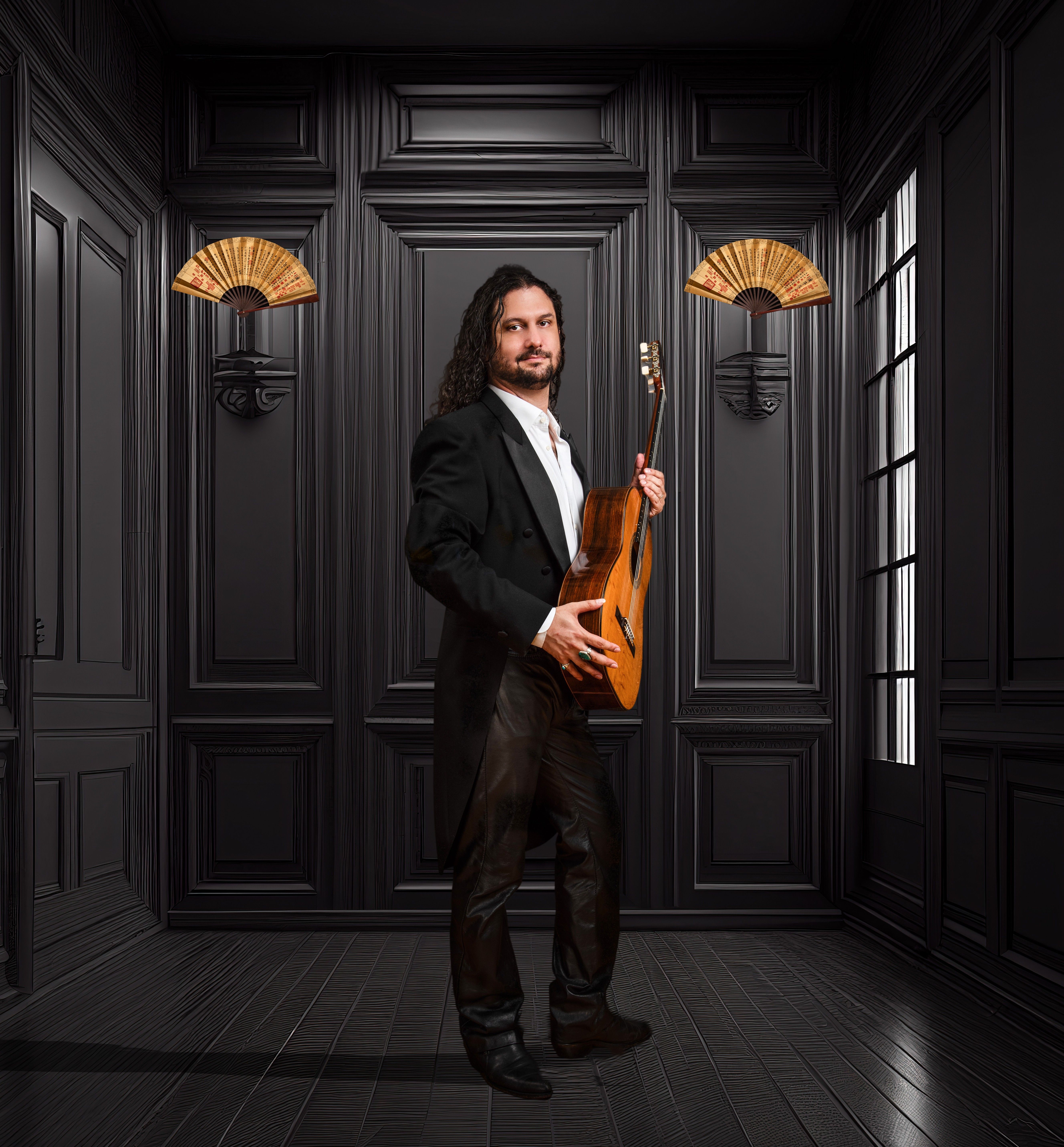 Man dressed in black holding a guitar and standing in a black room