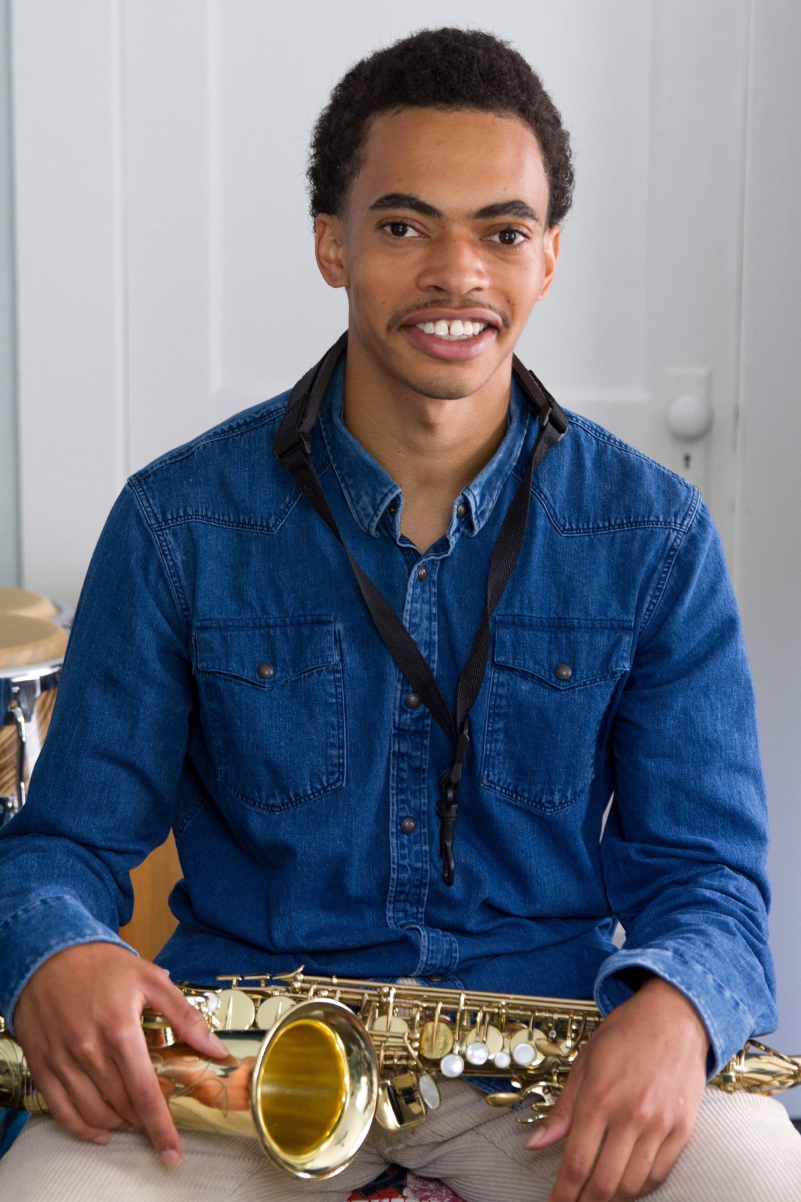 Man in blue shirt holding a saxophone