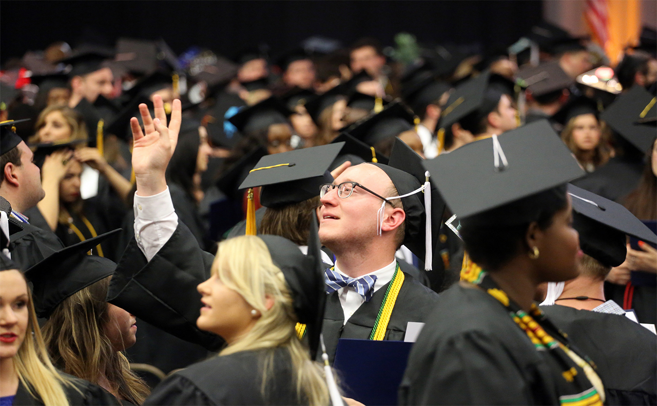 Student waiving at commencement