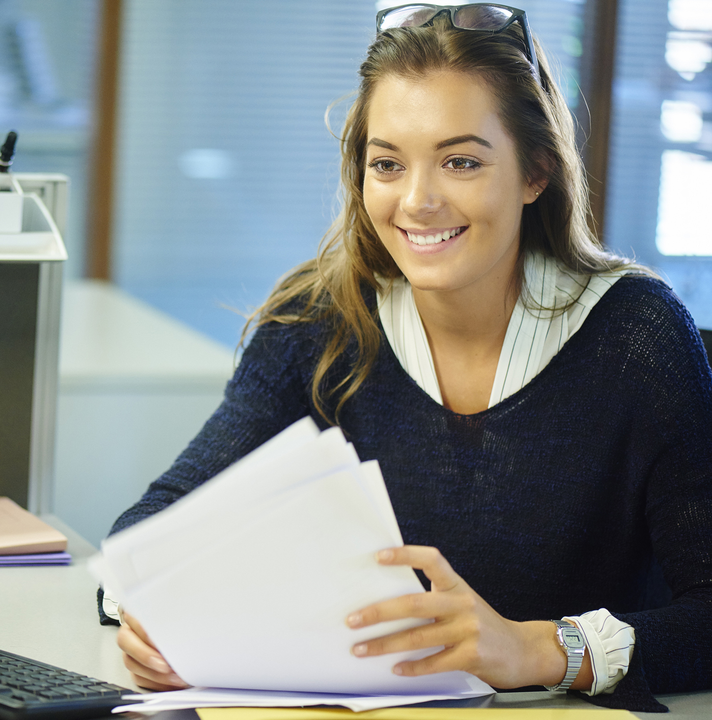 A student smiling while seated handling paperwork