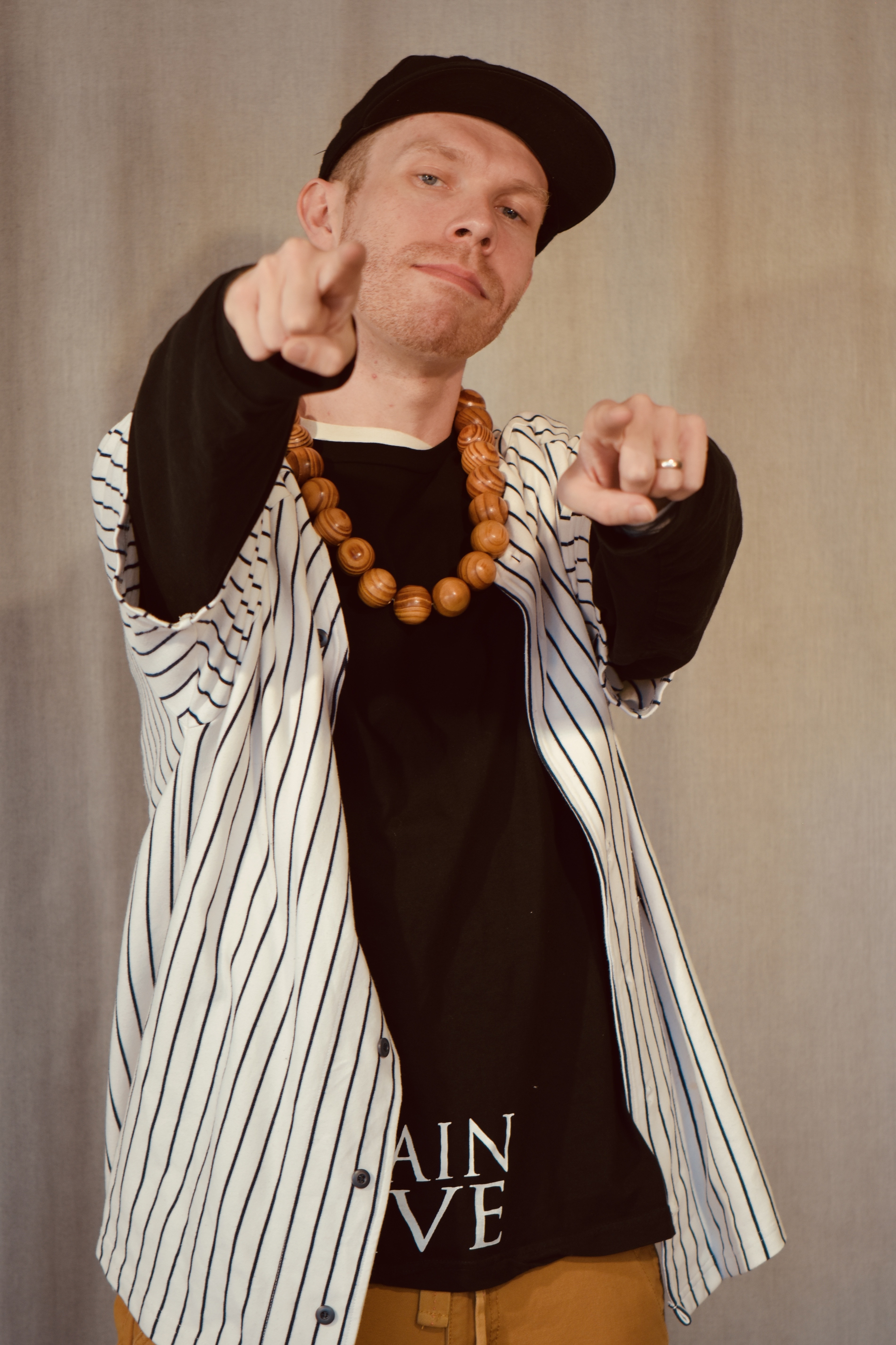 Man wearing baseball cap and baseball shirt pointing forward