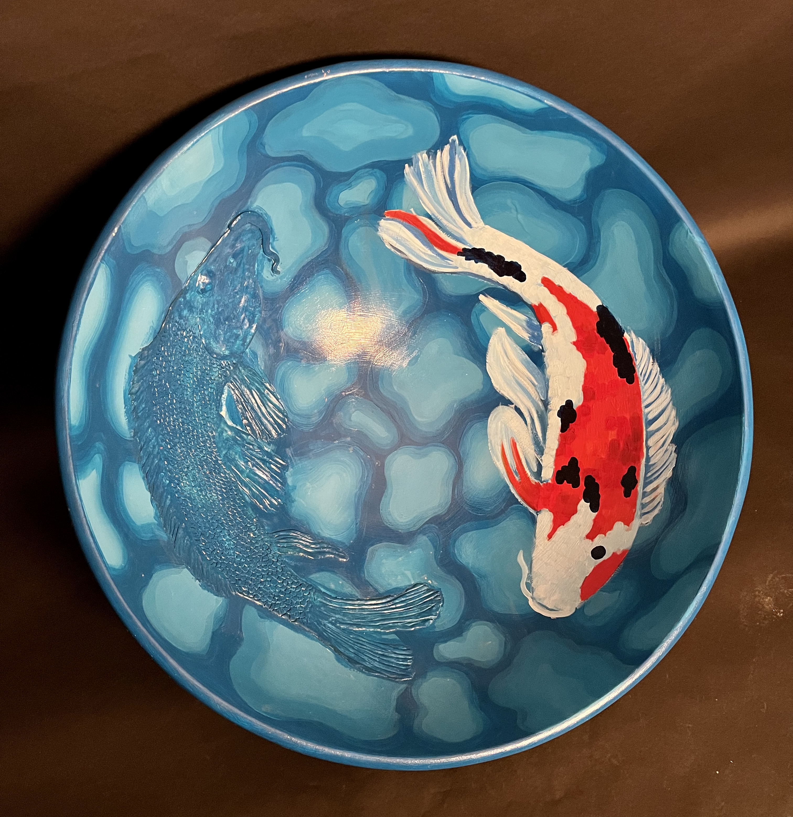 A blue bowl with an orange fish on it