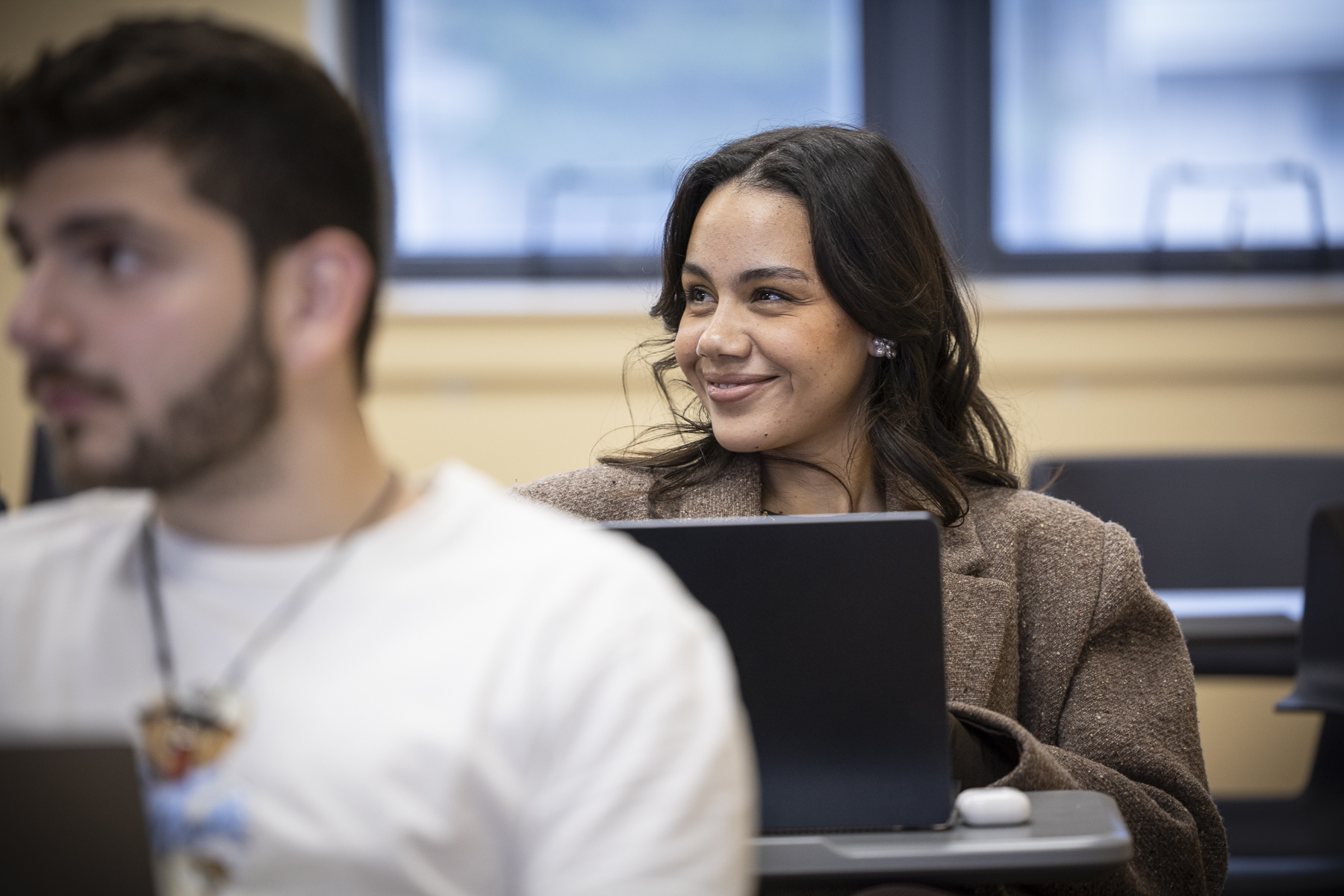 Female student in business dress, smiling in a classroom setting