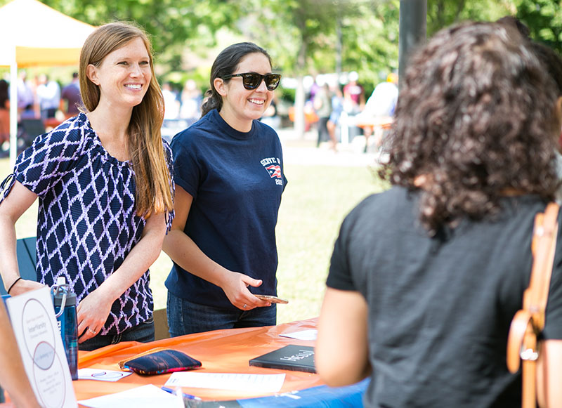 Two student leaders greet prospective members at the student organizations fair