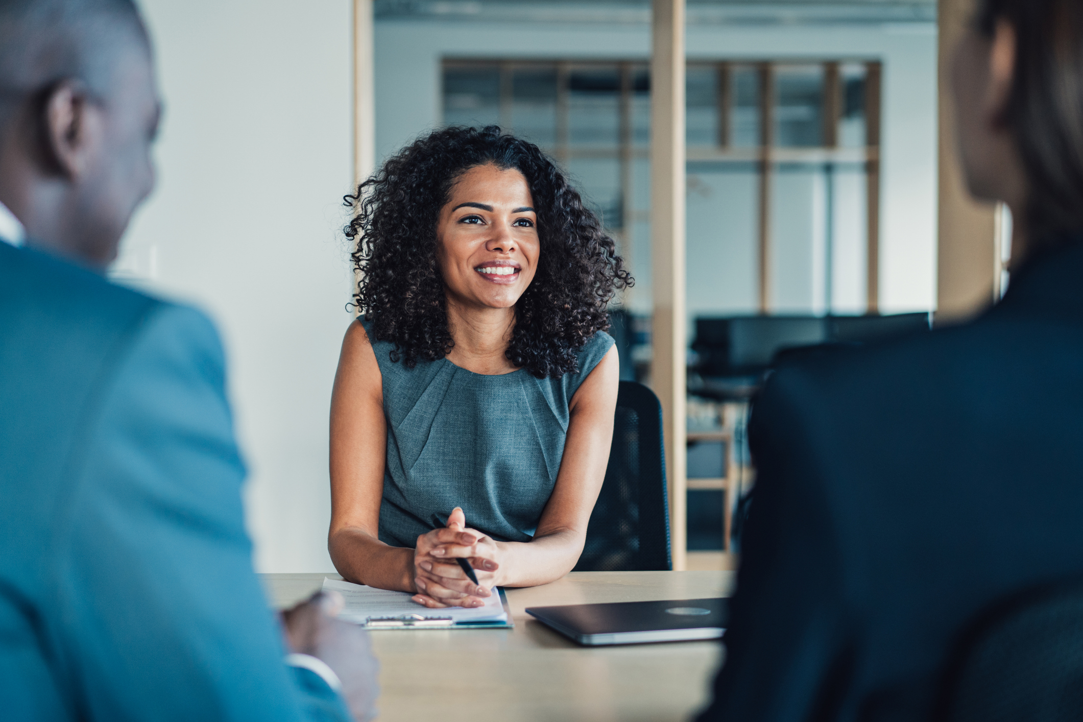 A woman smiling at two people across a conference table