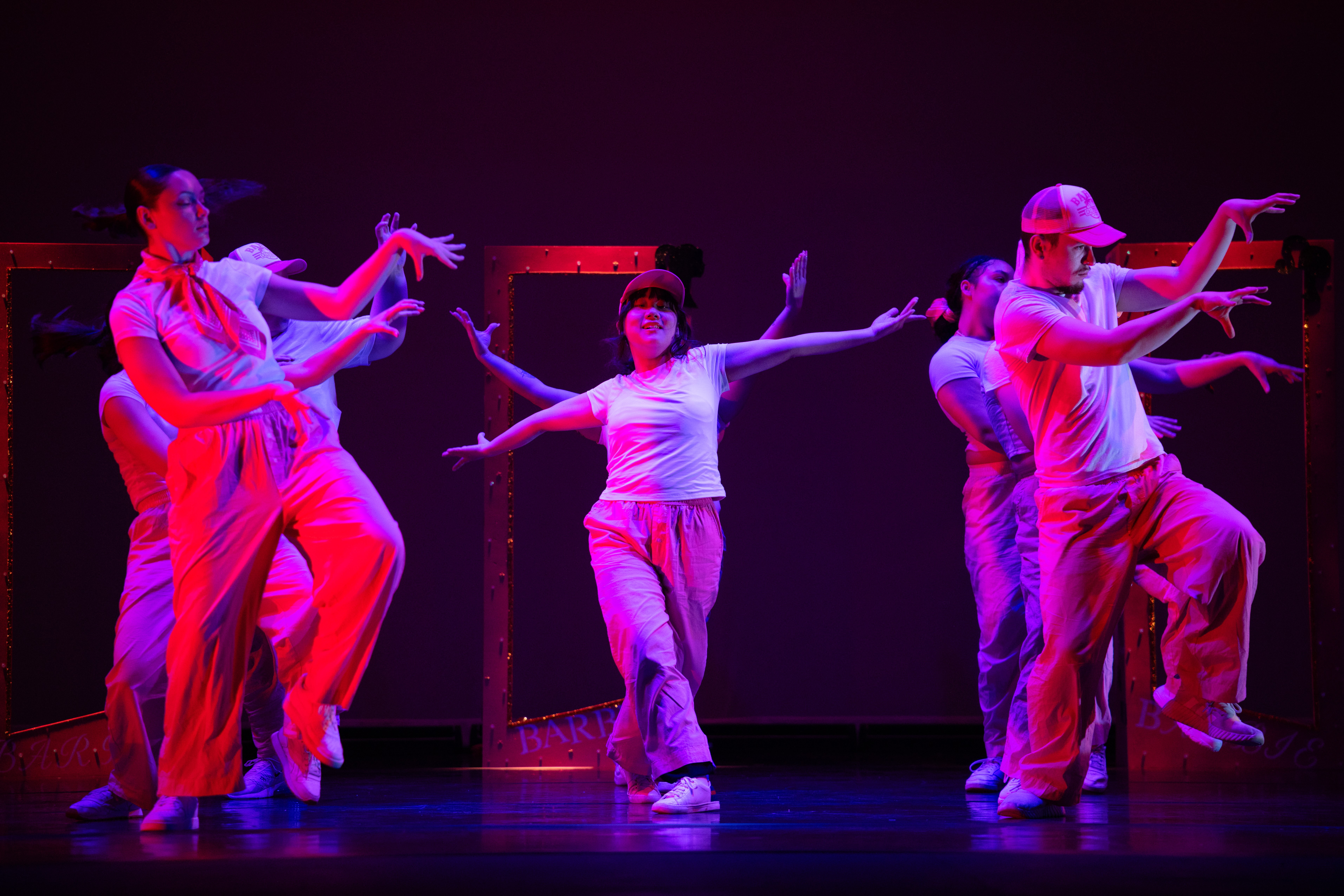Six dancers in pink light on the stage