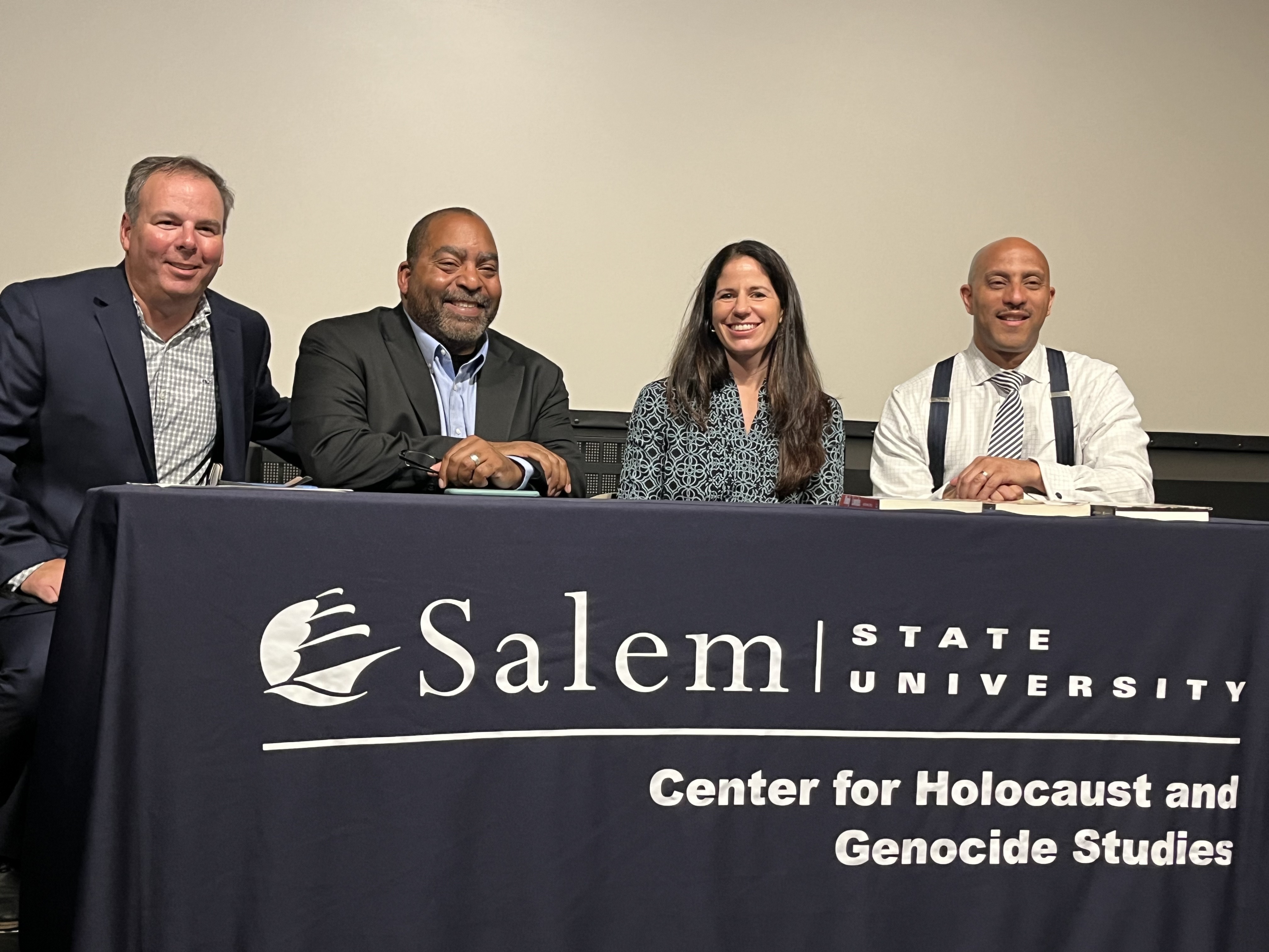 Four panel members sit at a Center for Holocaust and Genocide Studies table