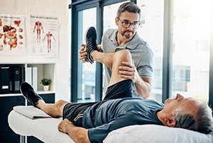 An athletic trainer bends the knee of an athlete on the training table