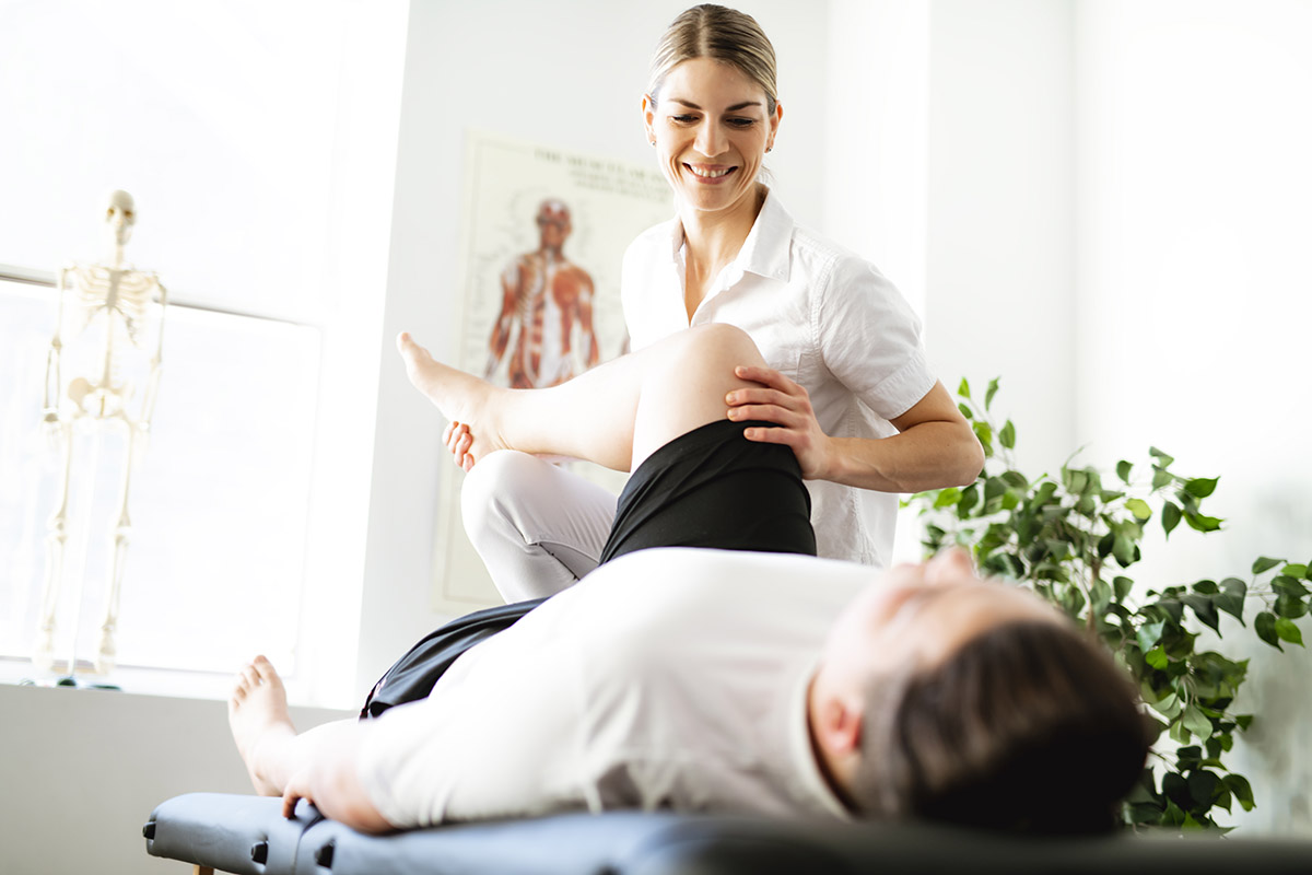 A female athletic trainer examines a knee on the training table