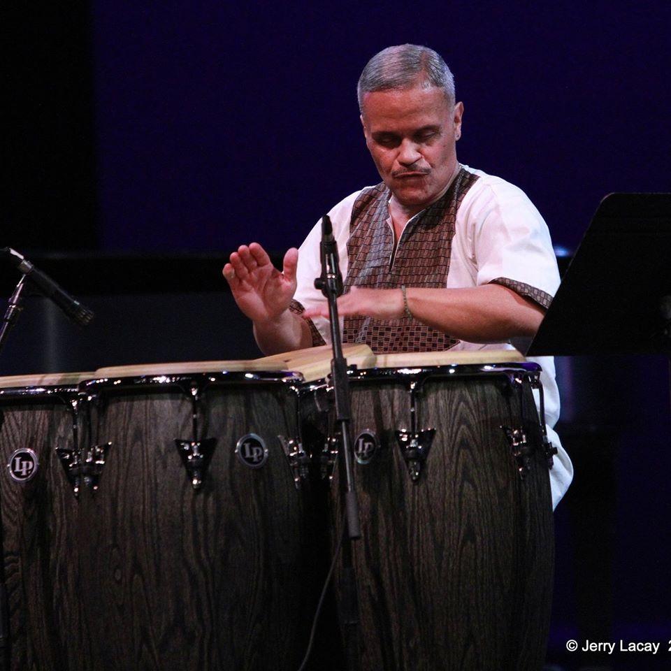 Man in a vest playing a conga drum