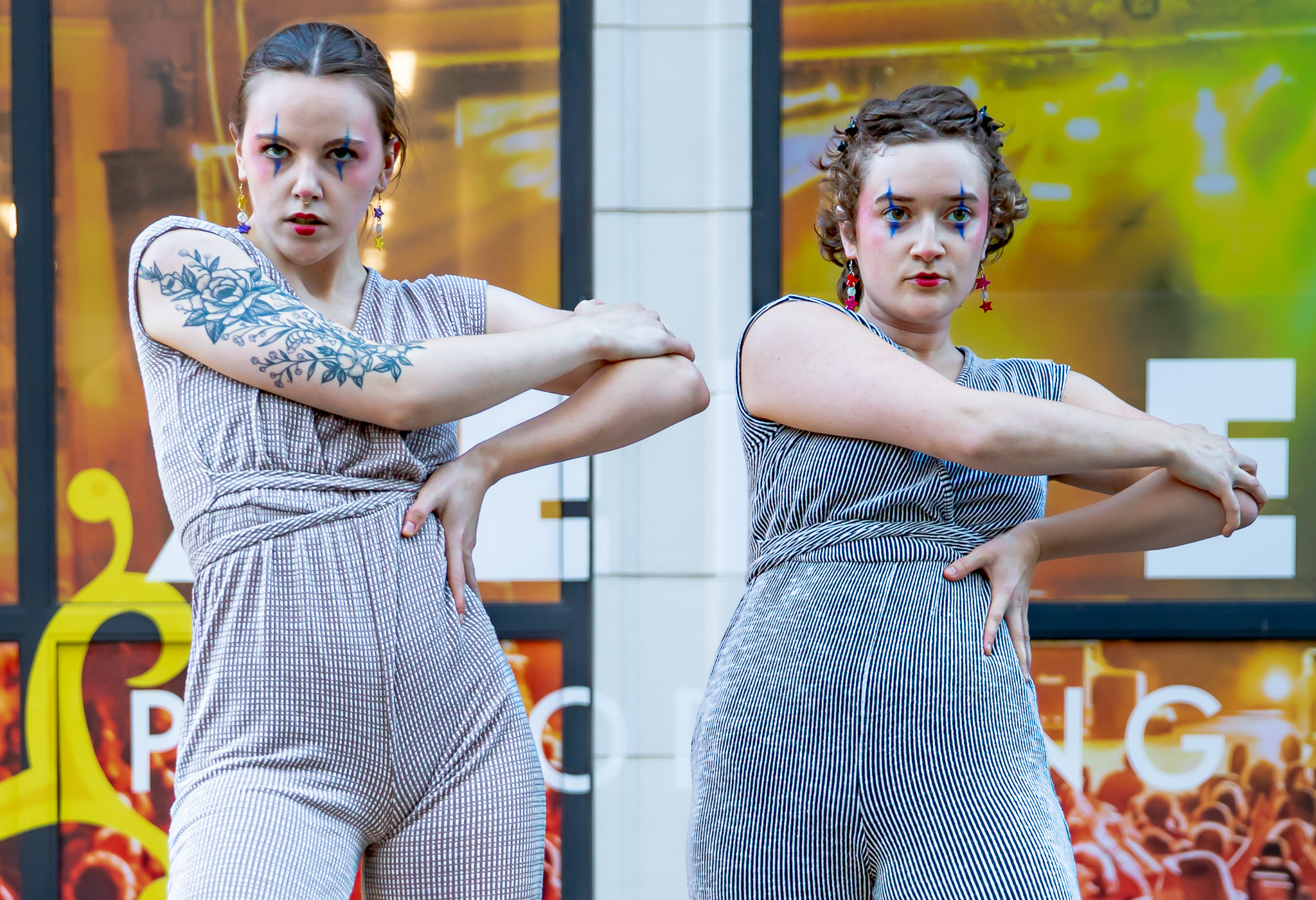 Two dancers in gray with their right arms across their bodies