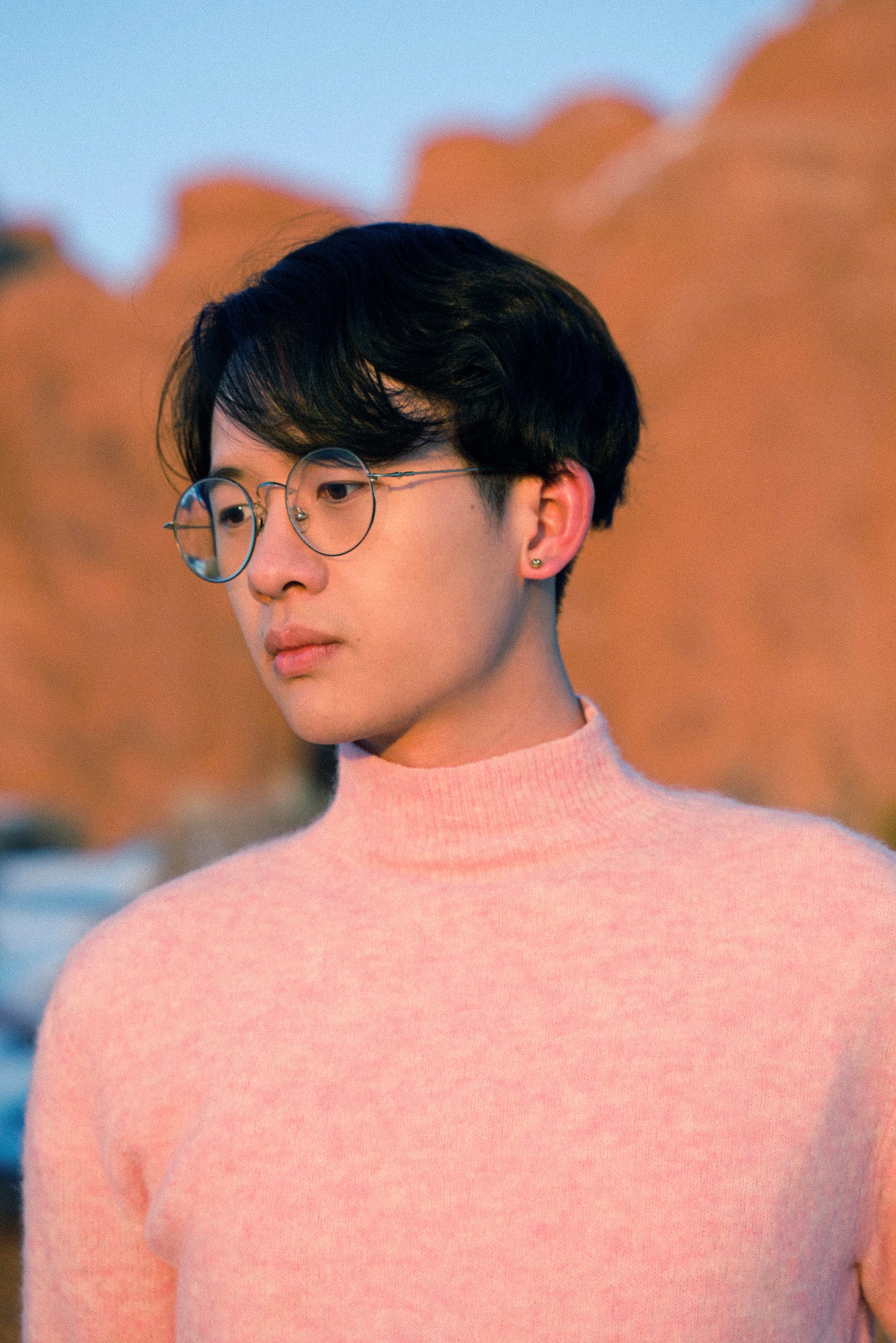 Dark haired person wearing glasses and a pink turtleneck