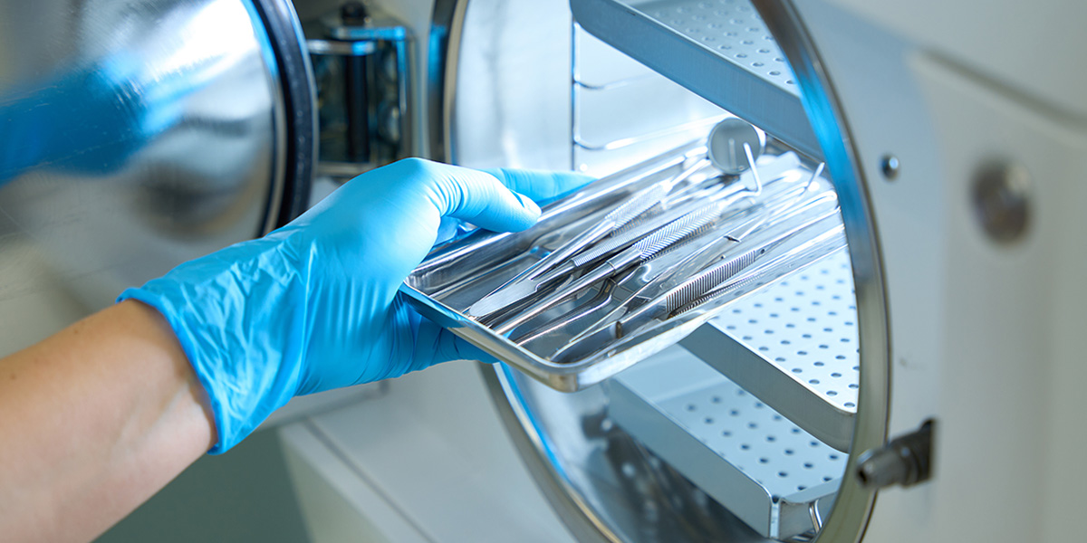 someone wearing blue medical gloves puts medical surgery tools in a medical container