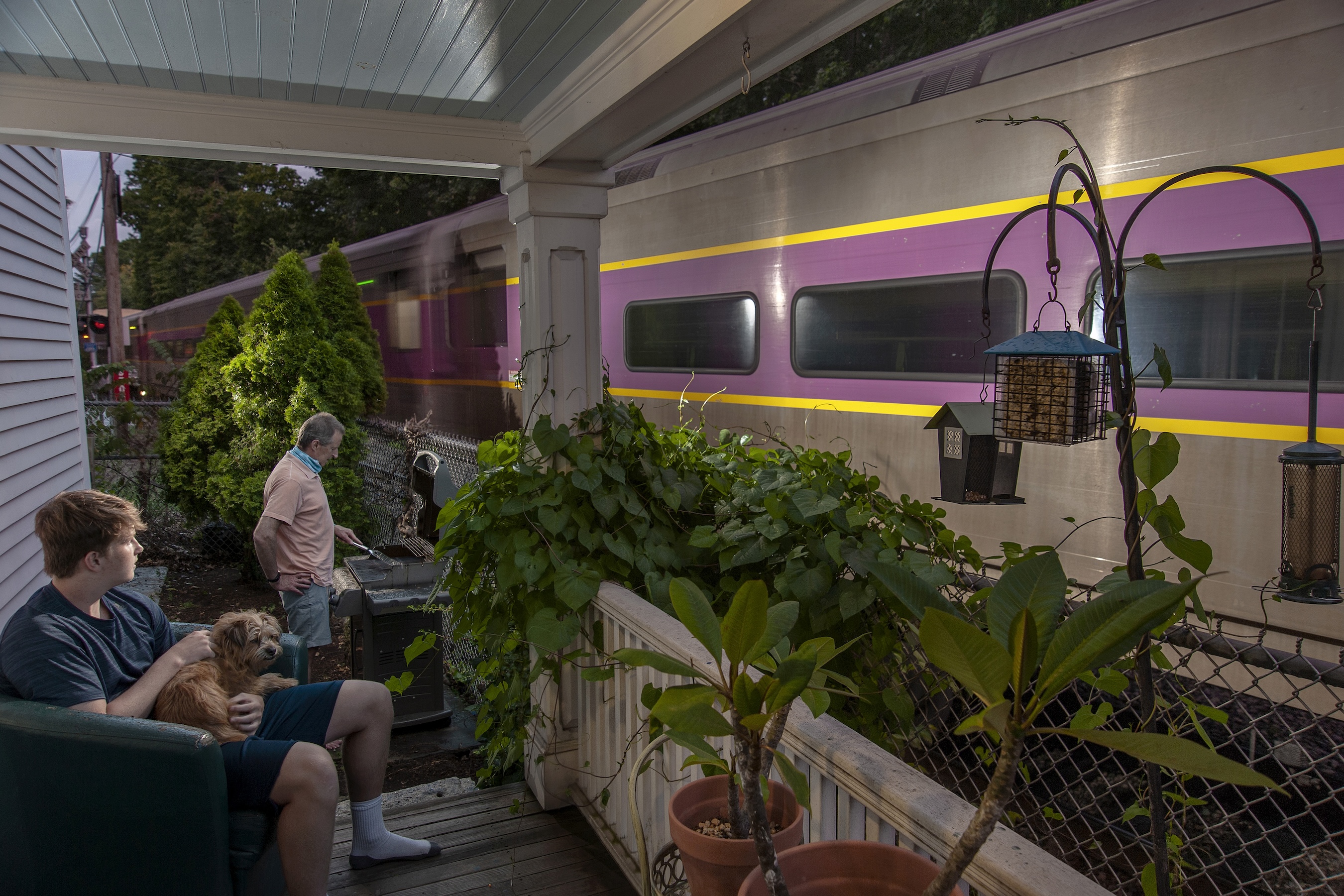 Two men sitting on a porch as a train passes by