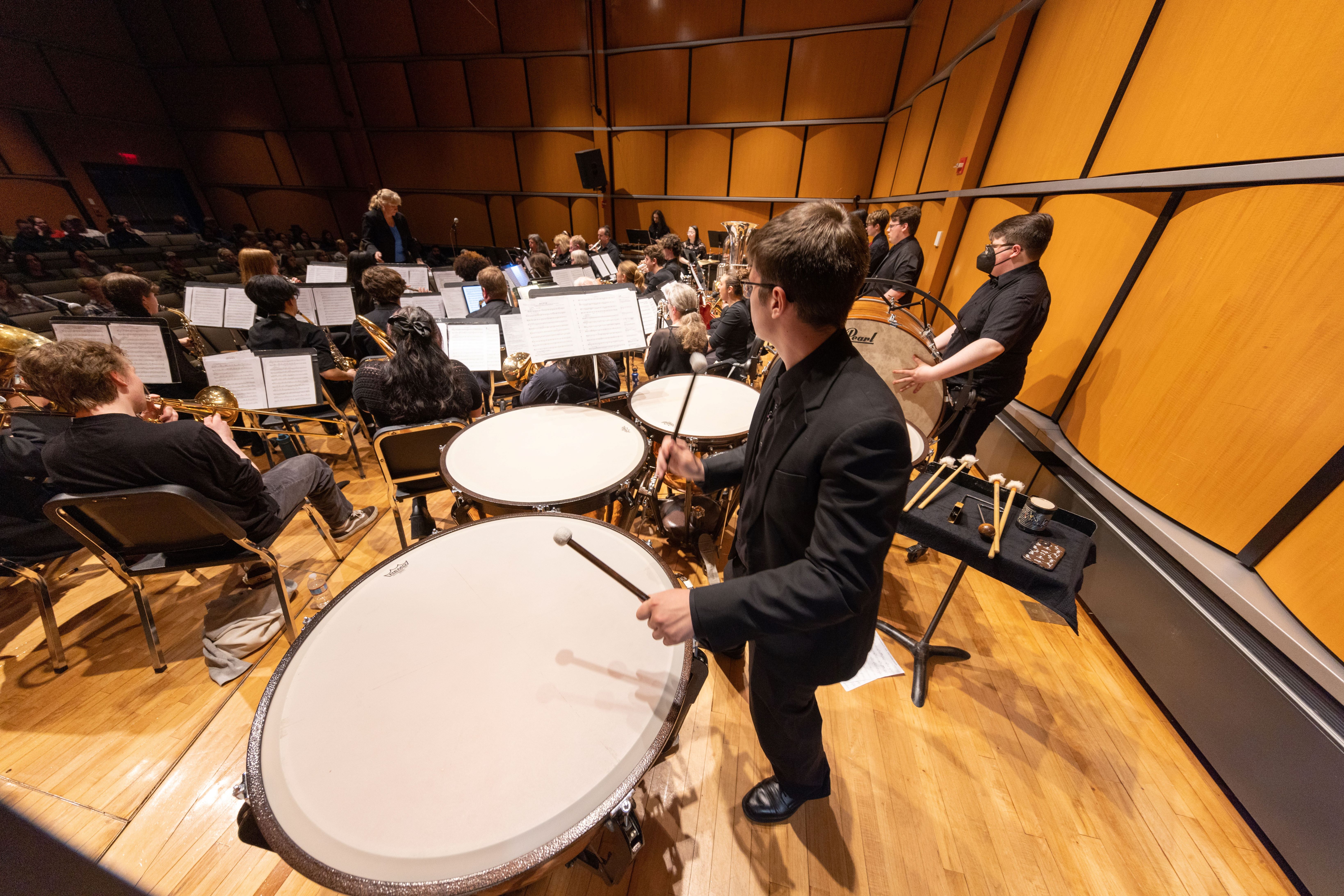 Person playing a timpani and other percussion instruments
