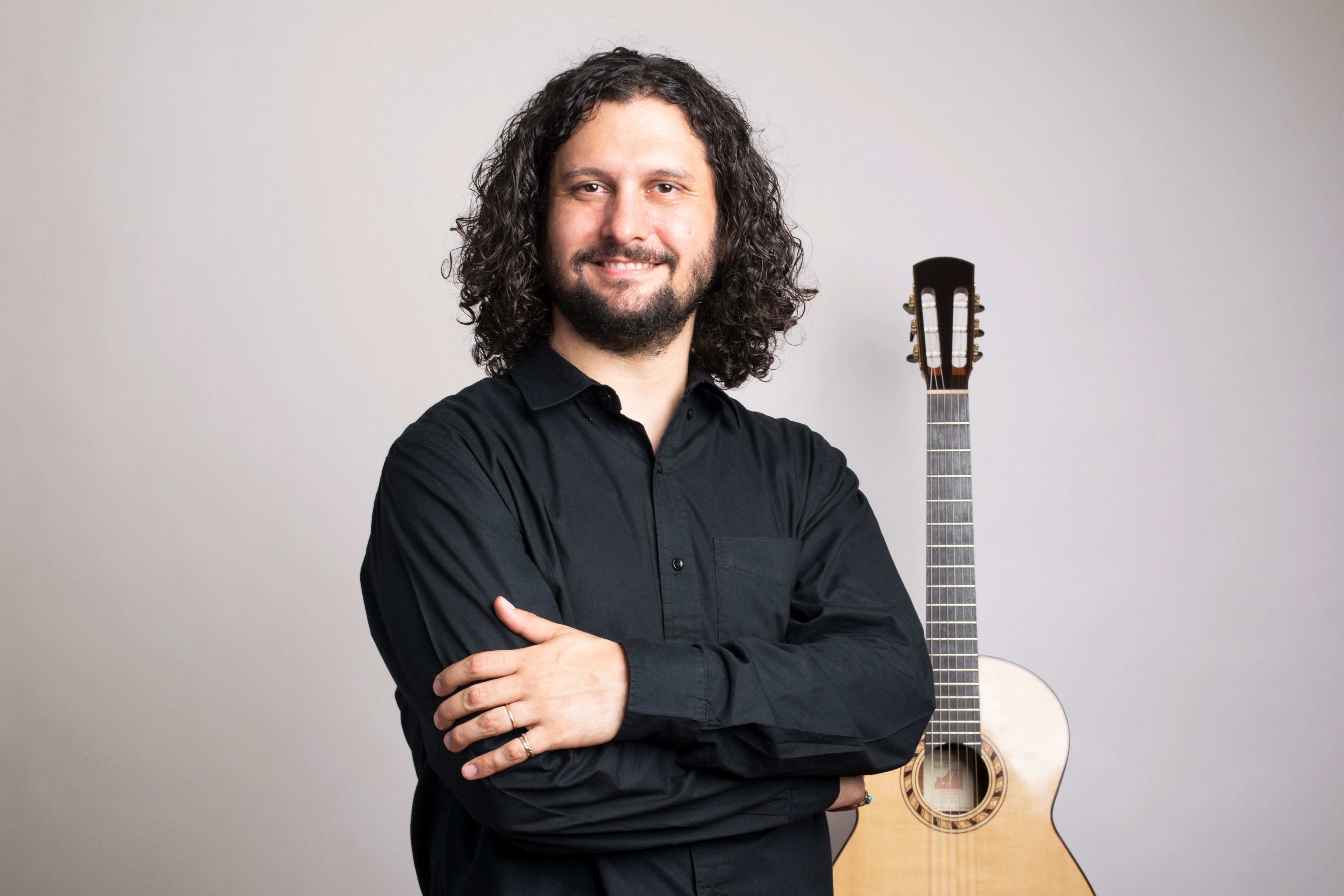 Man wearing black shirt and holding a guitar