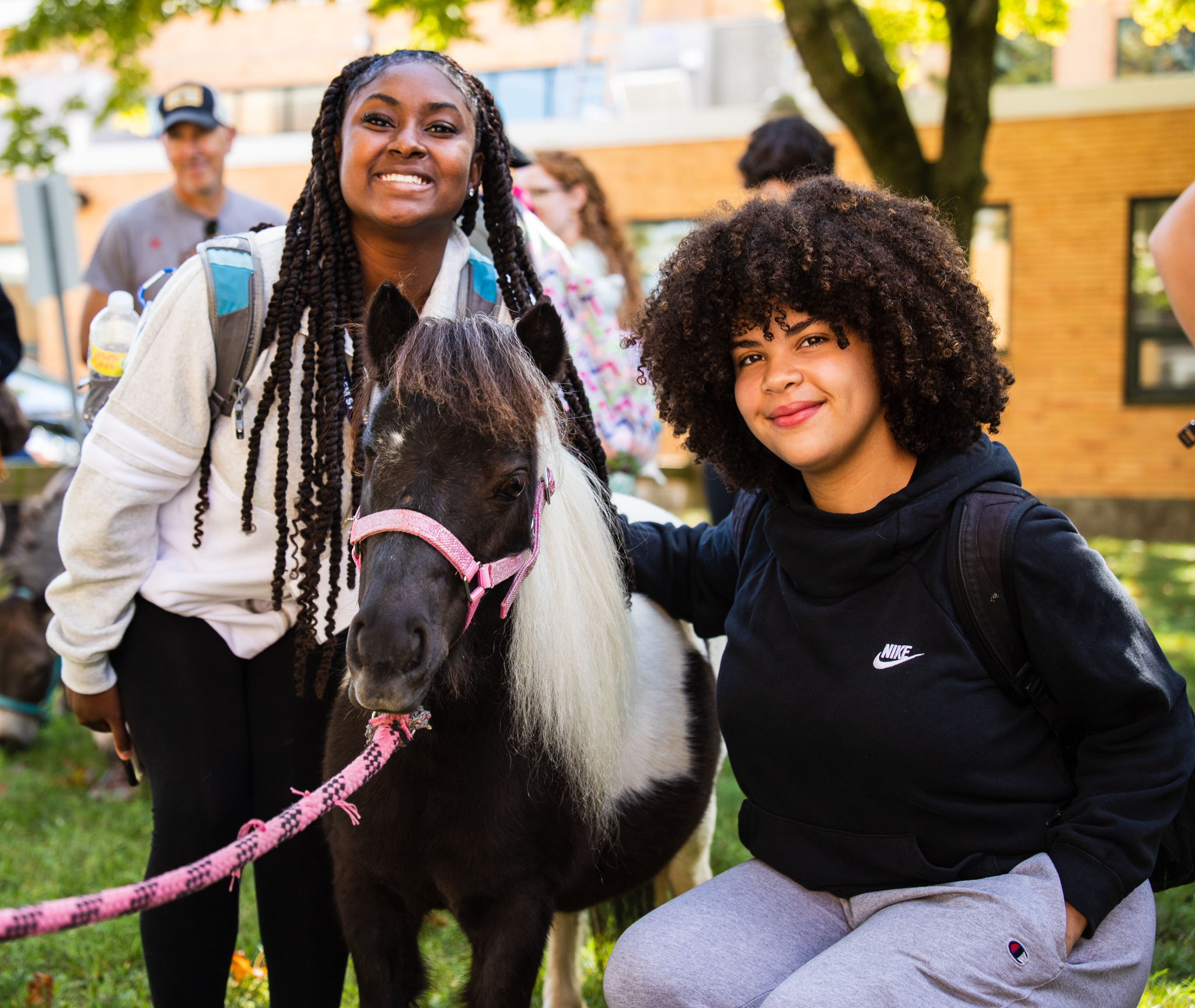 Two students pose with a miniature horse.