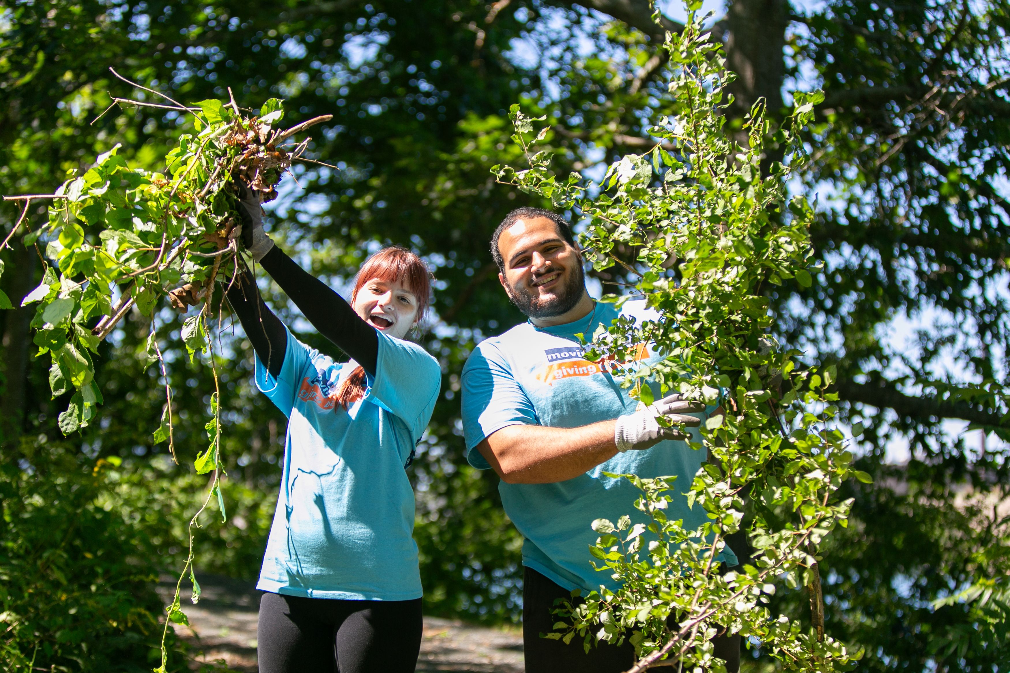 Two students holding up bittersweet plants that they removed off Winter Island