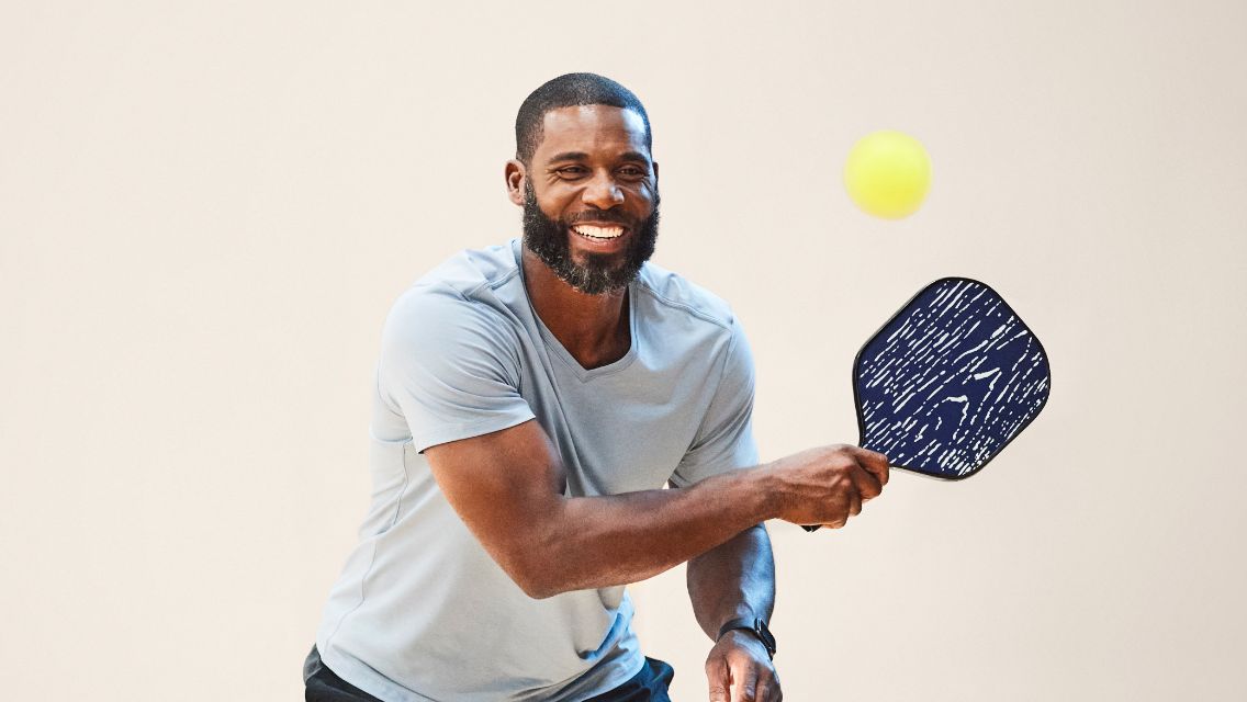 Pickleball player holding paddle aiming for ball