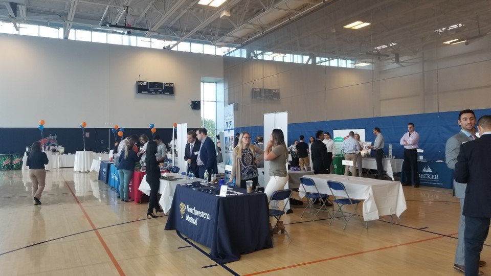 Career Fair in Gassett Gym with students visiting employers at tables in the Re…