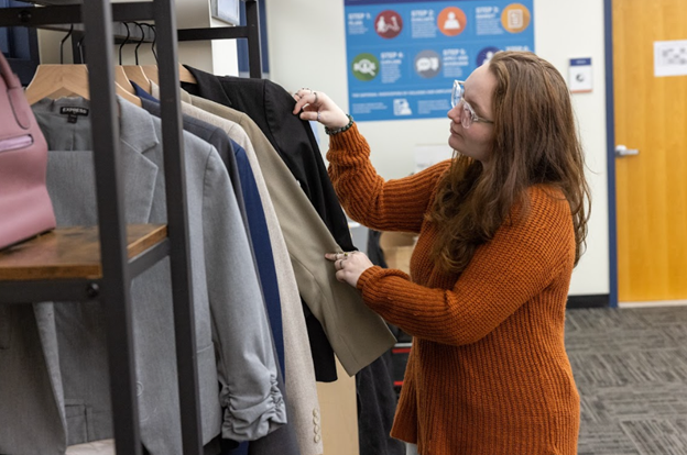 Student looking through racks of clothing at the Career Closet