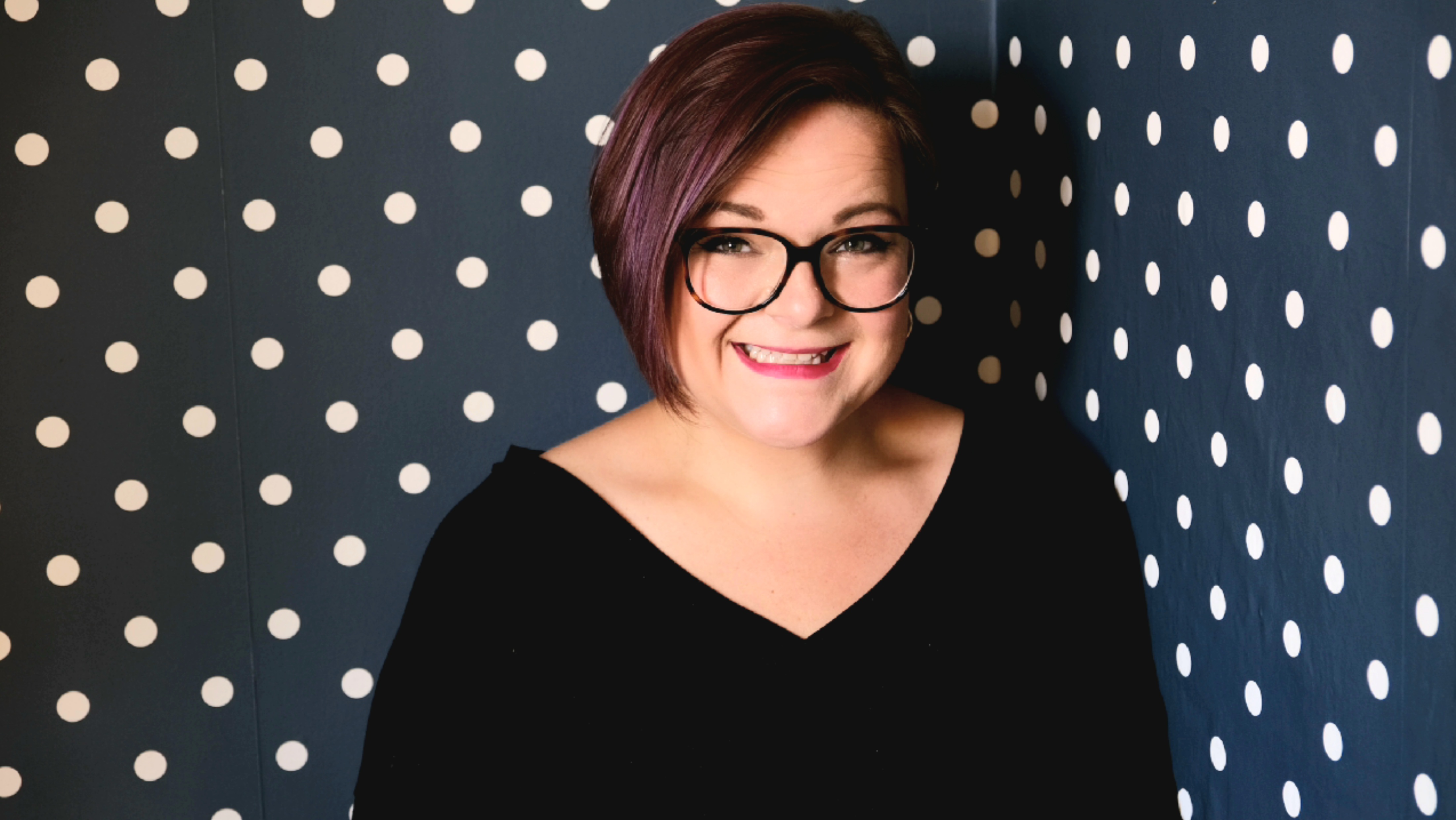 Justine Bodek headshot. Justine smiles in front of a polka dot background.