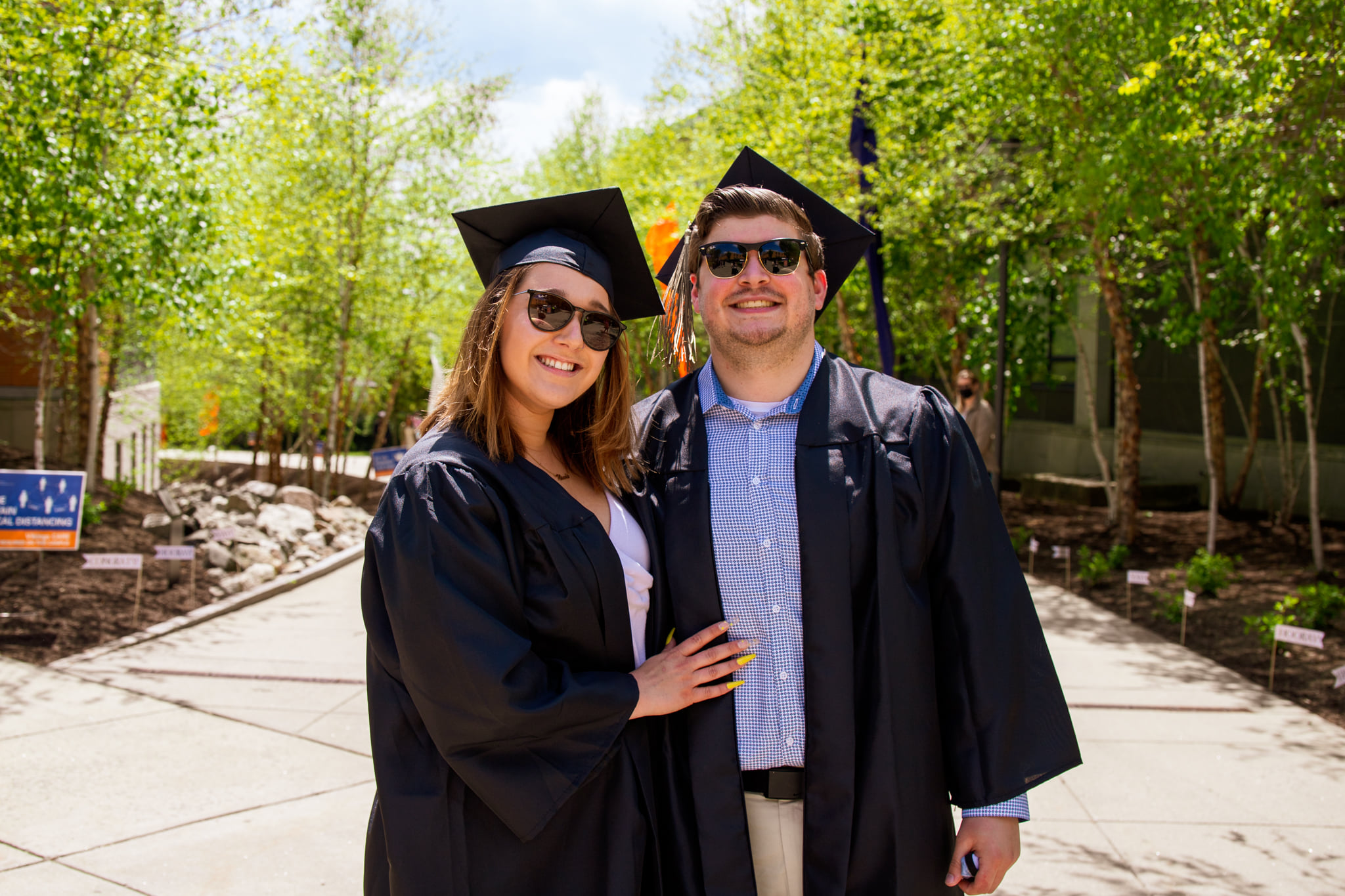 Two graduates smiling on campus