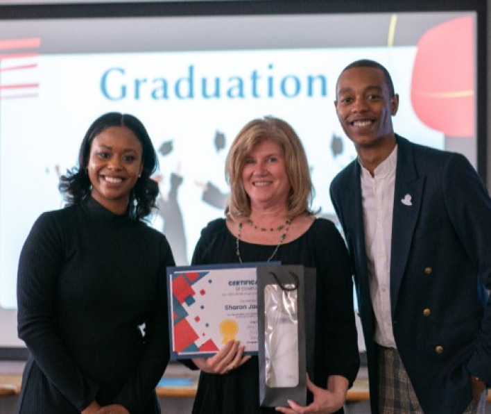 Two women and one man smiling in front of a screen