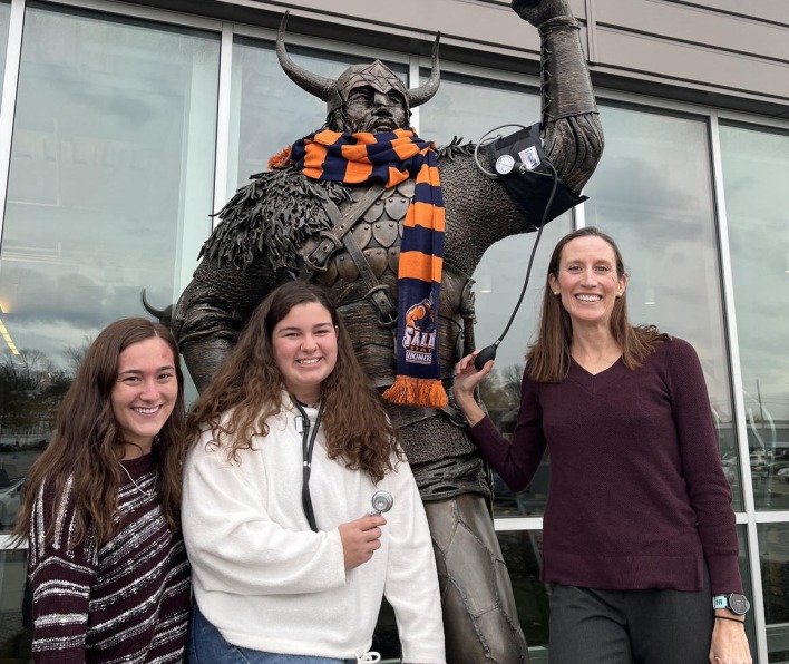 Brett Ely stands with students in front of the Viking statue.