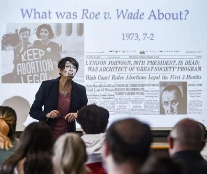 A speaker in front of a group and a presentation on Roe v. Wade