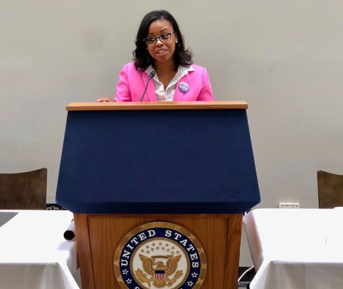 Erin Douglas, a 2018 Salem State alum, stands at a podium. 
