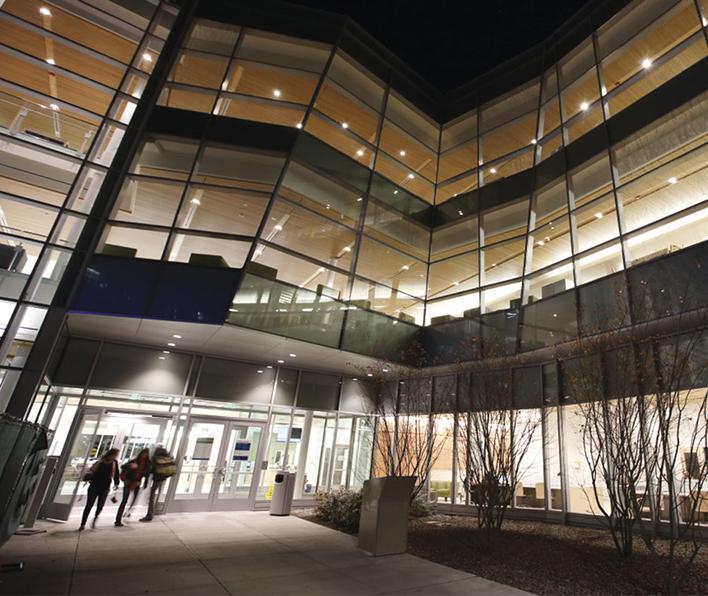 wide angle shot of students walking into the front door of the library at night