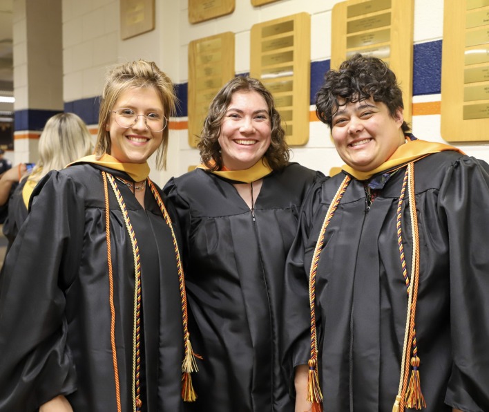 Three smiling graduate students at commencement