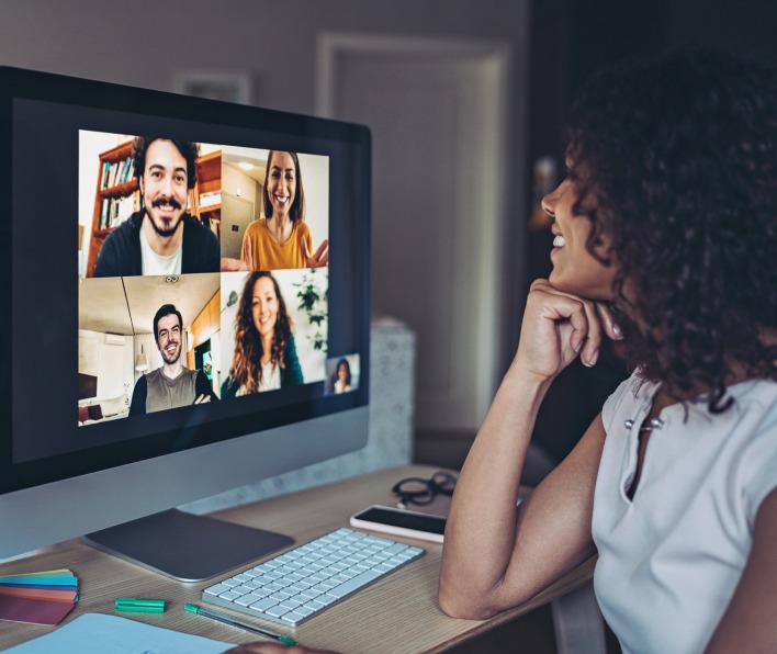 A woman smiling at a Zoom conference on screen