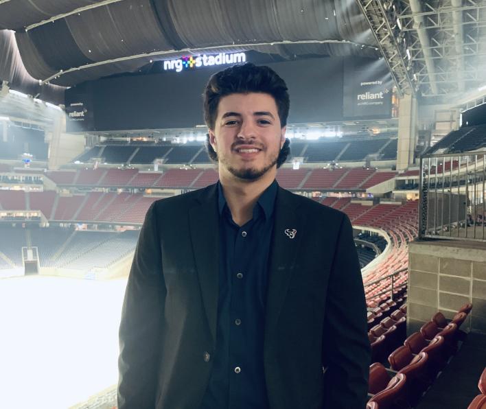 Photo of Stephen Guttadauro standing in the seats at a sports arena.