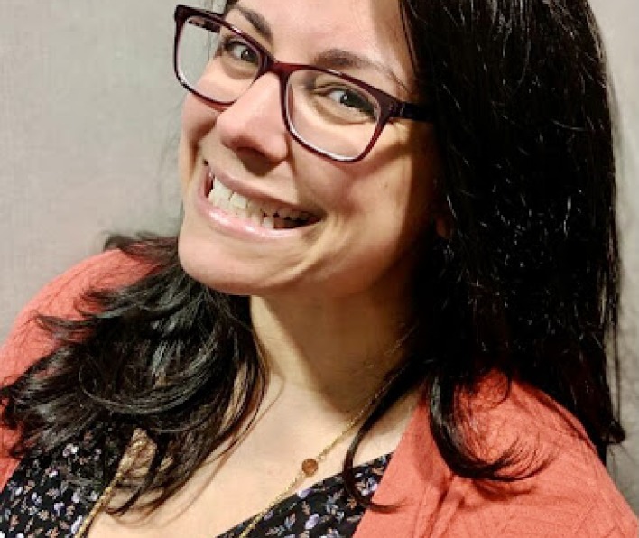 Young woman with brown hair and glasses, smiling