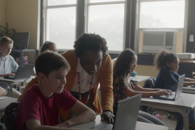 Teacher in an elementary classroom working with a young student