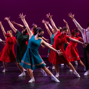 Dancers in colorful close with arms and legs extended
