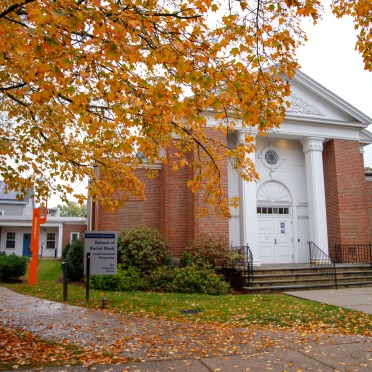 Social Work building with fall tree leaves in front of it.