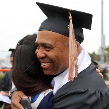 A Salem State graduate hugging a family member